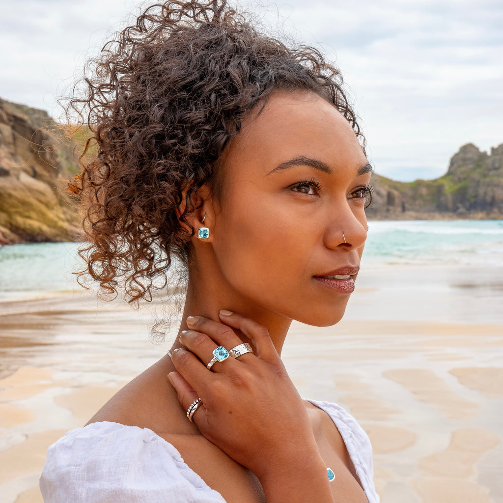 Close up of model's head and hand wearing rings and earrings